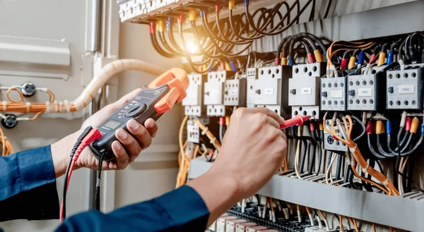 Elektrik mühendisi elektrik sistemi kontrol dolabındaki elektrik akımını ve elektrik hattını test etmek için çoklu metre kullanıyor..