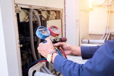 Teknisyen klimayı kontrol ediyor, klimaları doldurmak için ekipmanları ölçüyor..
