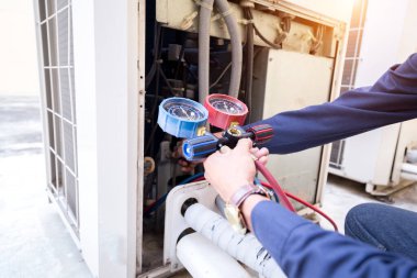 Teknisyen klimayı kontrol ediyor, klimaları doldurmak için ekipmanları ölçüyor..
