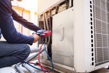 Teknisyen klimayı kontrol ediyor, klimaları doldurmak için ekipmanları ölçüyor..