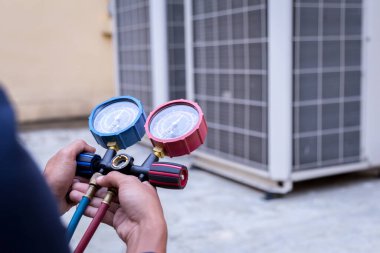 Teknisyen klimayı kontrol ediyor, klimaları doldurmak için ekipmanları ölçüyor..