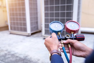 Teknisyen klimayı kontrol ediyor, klimaları doldurmak için ekipmanları ölçüyor..