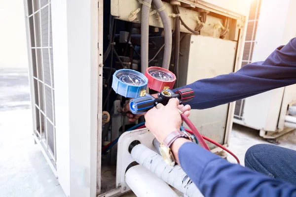 Teknisyen klimayı kontrol ediyor, klimaları doldurmak için ekipmanları ölçüyor..