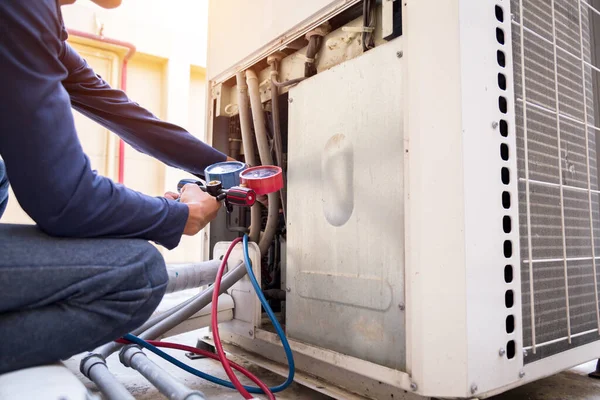 Teknisyen klimayı kontrol ediyor, klimaları doldurmak için ekipmanları ölçüyor..