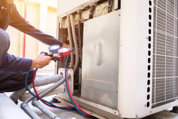 Teknisyen klimayı kontrol ediyor, klimaları doldurmak için ekipmanları ölçüyor..
