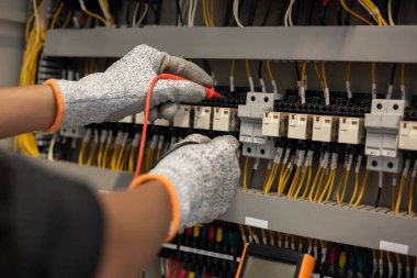 Elektrik mühendisi elektrik sistemi kontrol dolabındaki elektrik akımını ve elektrik hattını test etmek için çoklu metre kullanıyor..