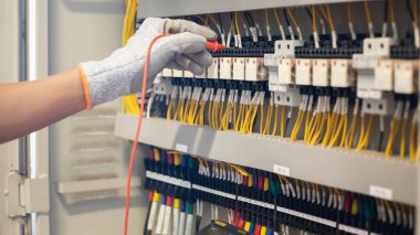 Elektrik mühendisi elektrik sistemi kontrol dolabındaki elektrik akımını ve elektrik hattını test etmek için çoklu metre kullanıyor..