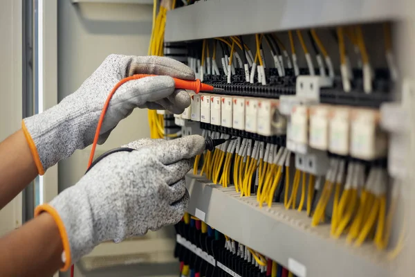 Elektrik mühendisi elektrik sistemi kontrol dolabındaki elektrik akımını ve elektrik hattını test etmek için çoklu metre kullanıyor..