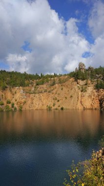 Etrafı su ve ağaçlarla dolu terk edilmiş bir taş ocağı..