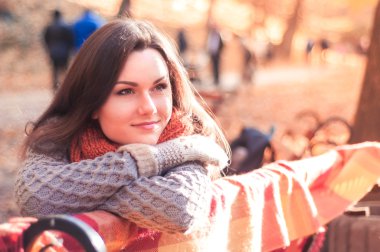 Örme kazak bir sonbahar parkta bir bankta oturan genç güzel kadın