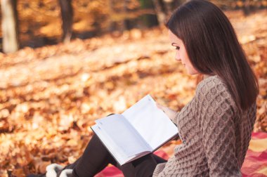 Bir halının üzerinde oturan ve kitap okuma kadın