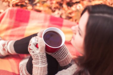 Bir halının üzerinde oturan ve çay içme genç kadın