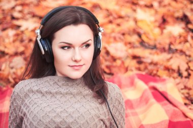 Bir sonbahar park bir halıya yatan ve th için dinleme genç kadın