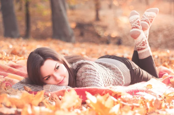 Молодая красивая женщина лежит на ковре в осеннем парке — стоковое фото