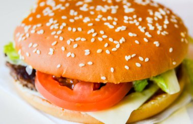 Sulu, lezzetli, baharatlı burger. Taze marulla doldurulmuş susamlı çöreğin iki yarısı, bir dilim domates, peynir, kızarmış dana pirzolası, İtalyan baharatlı aromalı ve narin bir sosla tatlandırılmış.