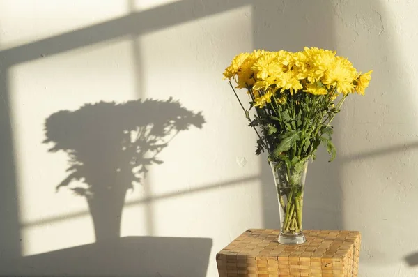 テーブルの上の花瓶に黄色の花の花束 壁に影 — ストック写真
