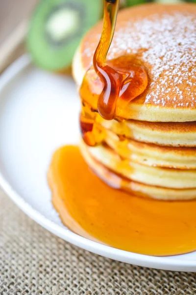 Versando sciroppo su pila di pancake su piastra bianca e sacco w — Foto Stock