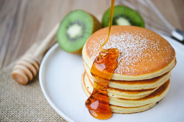 Pouring syrup on stack of pancake on white plate and sackcloth w — Stock Photo, Image