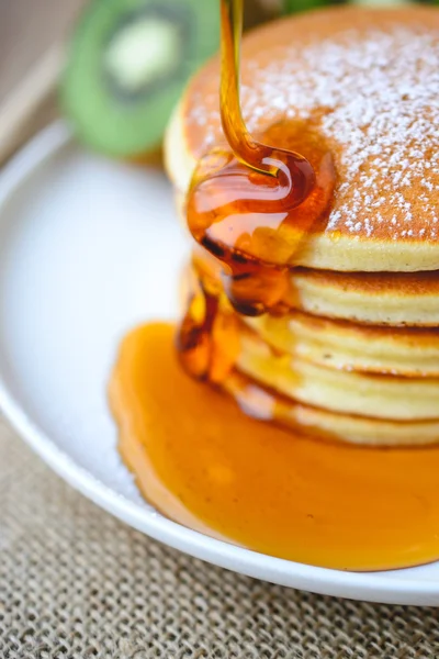 Gießen Sirup auf Stapel von Pfannkuchen auf weißem Teller und Sacktuch w — Stockfoto