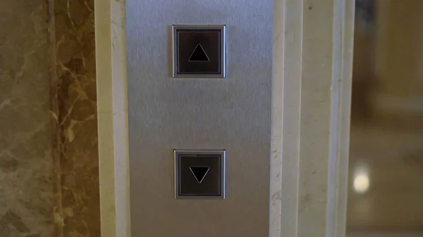 Elevator buttons on the floor, steel call panel. Two arrow buttons up and down.
