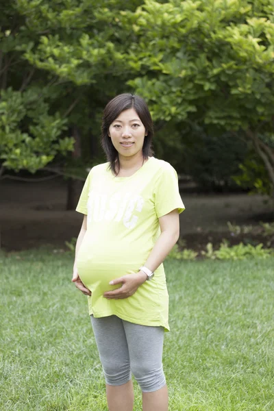 Feliz mujer embarazada china de pie al aire libre —  Fotos de Stock