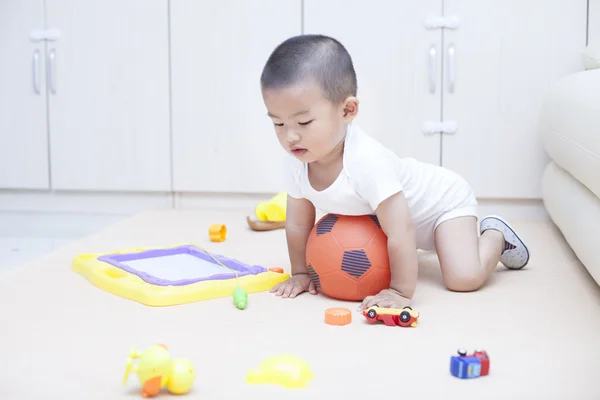 Cute Chinese baby boy playing a soccer ball indoors — Stock Photo, Image