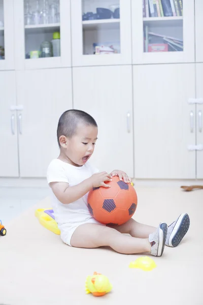Милый китайский мальчик играет в футбол в помещении — стоковое фото