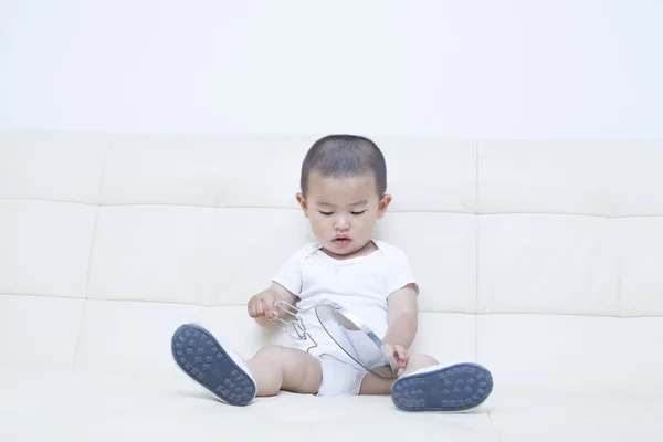 Милый китайский мальчик, играющий в зеркало на диване — стоковое фото