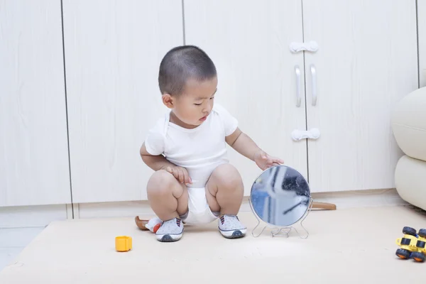 Bir ayna kanepe oynayan sevimli Çinli bebek çocuk