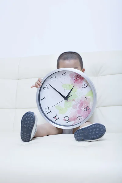 Cute Chinese baby boy playing a clock in sofa — Stock Photo, Image