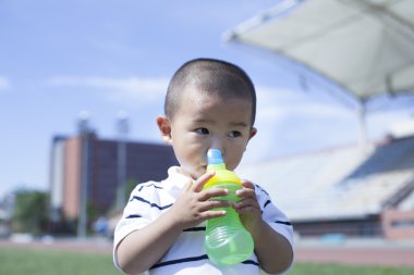 Şirin Çinli çocuk içme suyu bir stadyumda bebeğim