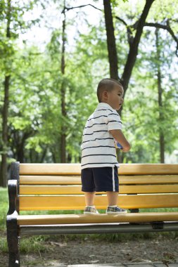 Ormanda bir bankta oynayan sevimli Çinli bebek çocuk