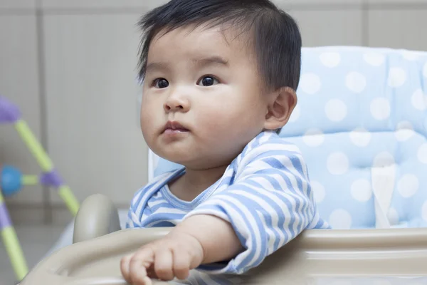 Милый китайский мальчик сидит в детском кресле — стоковое фото