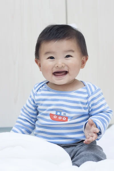 Милый китайский мальчик, сидящий на белом одеяле — стоковое фото
