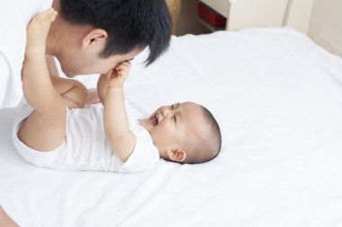 Chinese father and son playing in bed clipart
