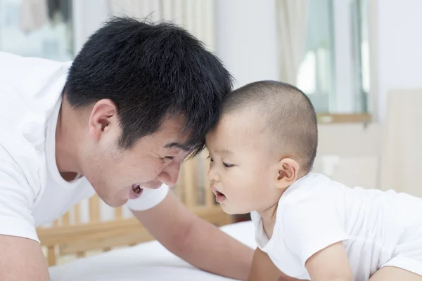 Real pai e filho chinês brincando na cama — Fotografia de Stock