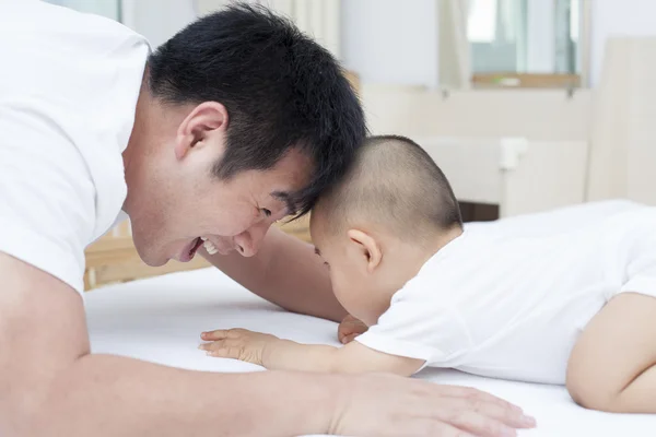 Real pai e filho chinês brincando na cama — Fotografia de Stock