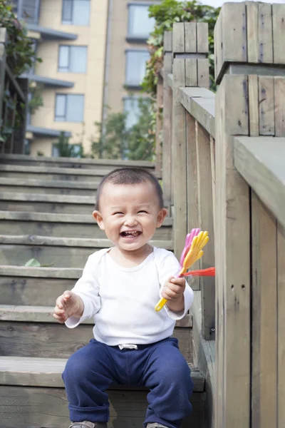 Счастливый китайский мальчик играет игрушку на лестнице — стоковое фото
