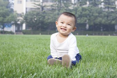 Çayır üzerinde oturan sevimli Çinli bebek çocuk