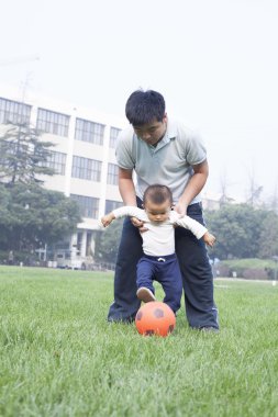 Çince baba ve oğul çayırda futbol oynamak