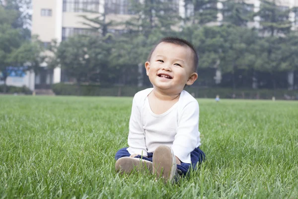 Lindo niño chino sentado en el prado — Foto de Stock