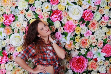 Genç romantik esmer kız çiçek duvarının yakınında