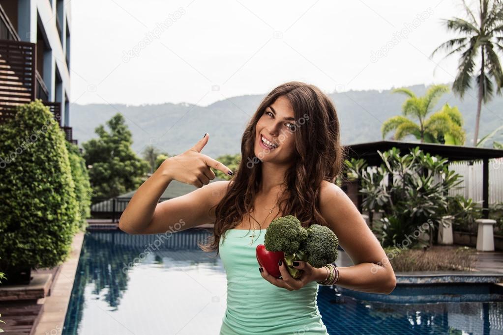 Detox diet: young beautiful girl sitandig outside with broccoli and red pepper