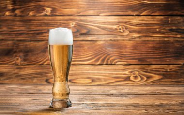 Ahşap bir masada bir bardak soğuk bira. Boşluğu kopyala