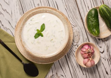 Gri arka planda Yunan tzatziki sosu. Geleneksel Hint raitası, salatalık, Yunan yoğurdu ve kişniş, üst manzara.