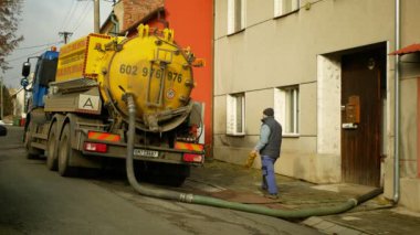 OLOMOUC, CZECH REPUBLIC, JANUARY, 20, 2021: Basınç altında boru tankı vakum hortumuna pompalanan foseptik boşaltma. İnsanlar işçi evlerinde köy, atık su kirliliği içeriyor.