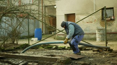 OLOMOUC, CZECH REPUBLIC, JANUARY, 20, 2021: Basınç altında boru tankı vakum hortumuna pompalanan foseptik boşaltma. İnsanlar işçi evlerinde köy, atık su kirliliği içeriyor.