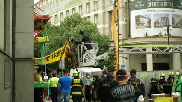 PRAGA, REPÚBLICA CHECA, 28 DE JUNIO DE 2021: Manifestación Extinción Rebelión protesta bloqueo bloqueo bloqueo Banco Nacional Checo, mujer atada detención encadenada edificio de cuerda activista climático policía antidisturbios — Vídeo de stock