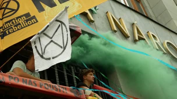 PRAGUE, REPÚBLICA CHECA, 28 DE JUNHO DE 2021: Manifestação Extinção Rebelião protesto bloqueio bloqueio bloqueio flara Bank, fumar fumaça bomba mulher amarrado acorrentado edifício clima ativista motim polícia — Vídeo de Stock