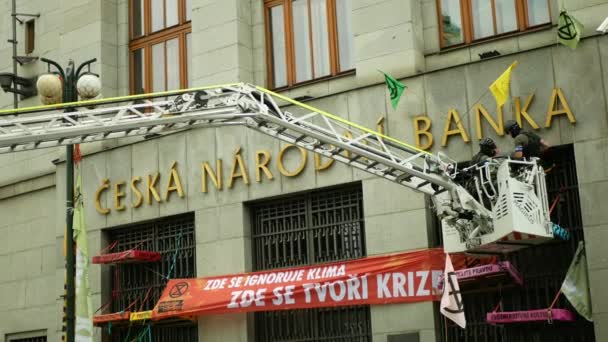 PRAAG, TSJECHIË, 28 JUNI 2021: Uitsterving Opstand demonstratieblokkade Tsjechische Nationale Bank, vastgebonden man vastgebonden touw gebouw klimaatactivist oproerpolitie — Stockvideo